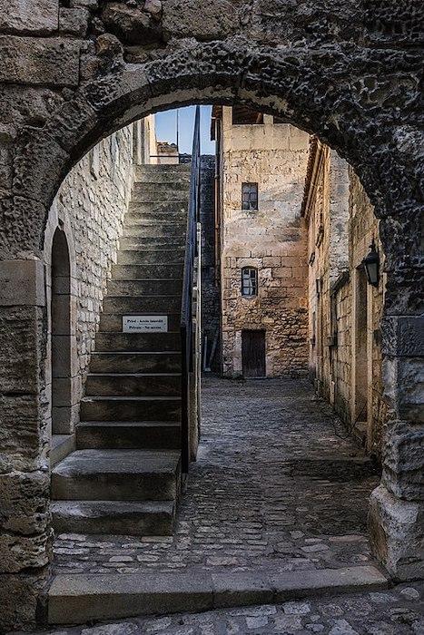 Un passage qui mène sur les escaliers extérieurs et dans une cour dans le village des Baux-de-Provence ©Christian Ferrer