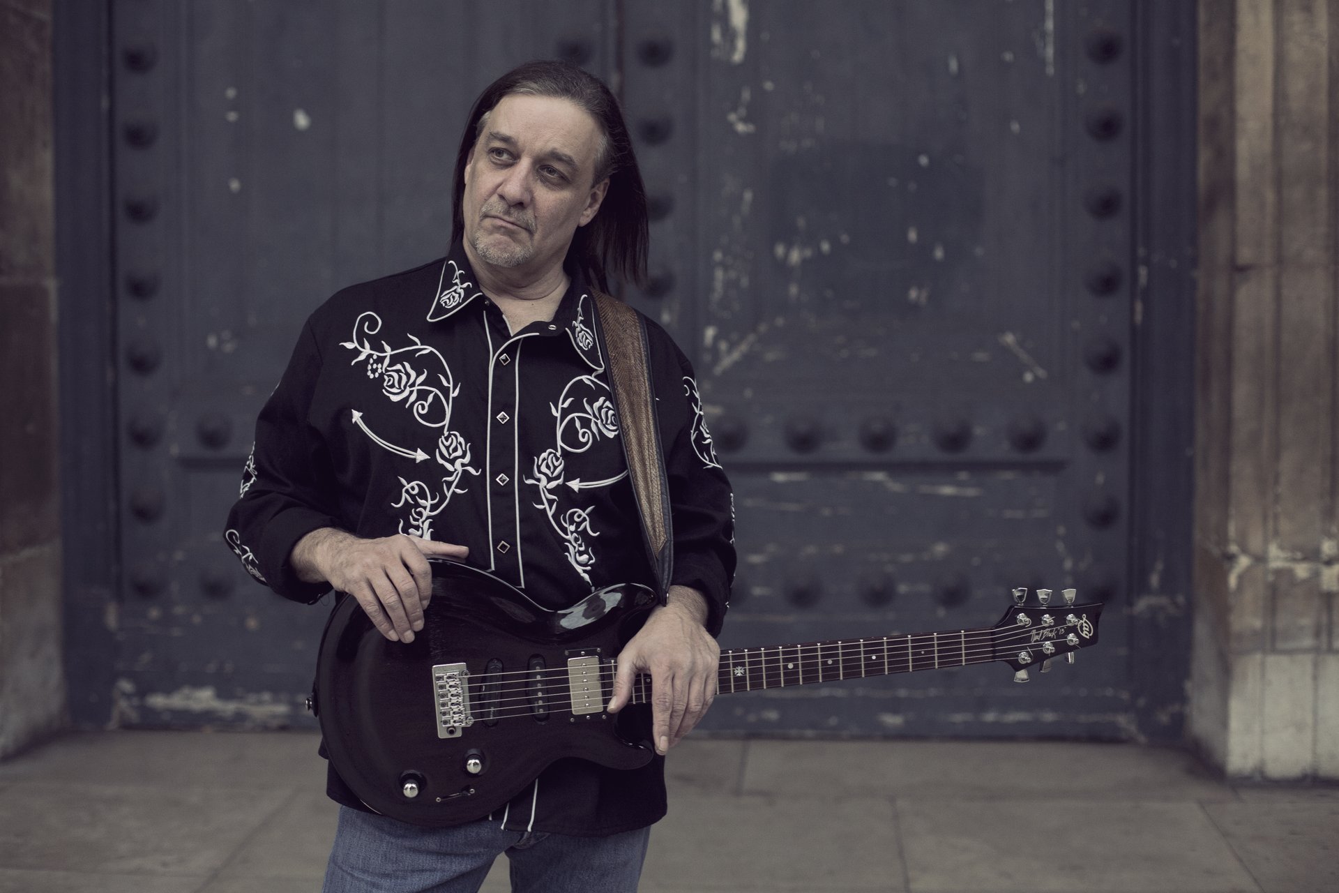 Le bluesman texan Neal Black pose avec sa guitare électrique noire ; il ouvre le programme des concerts d'octobre 2026 au Sonograf, au Thor